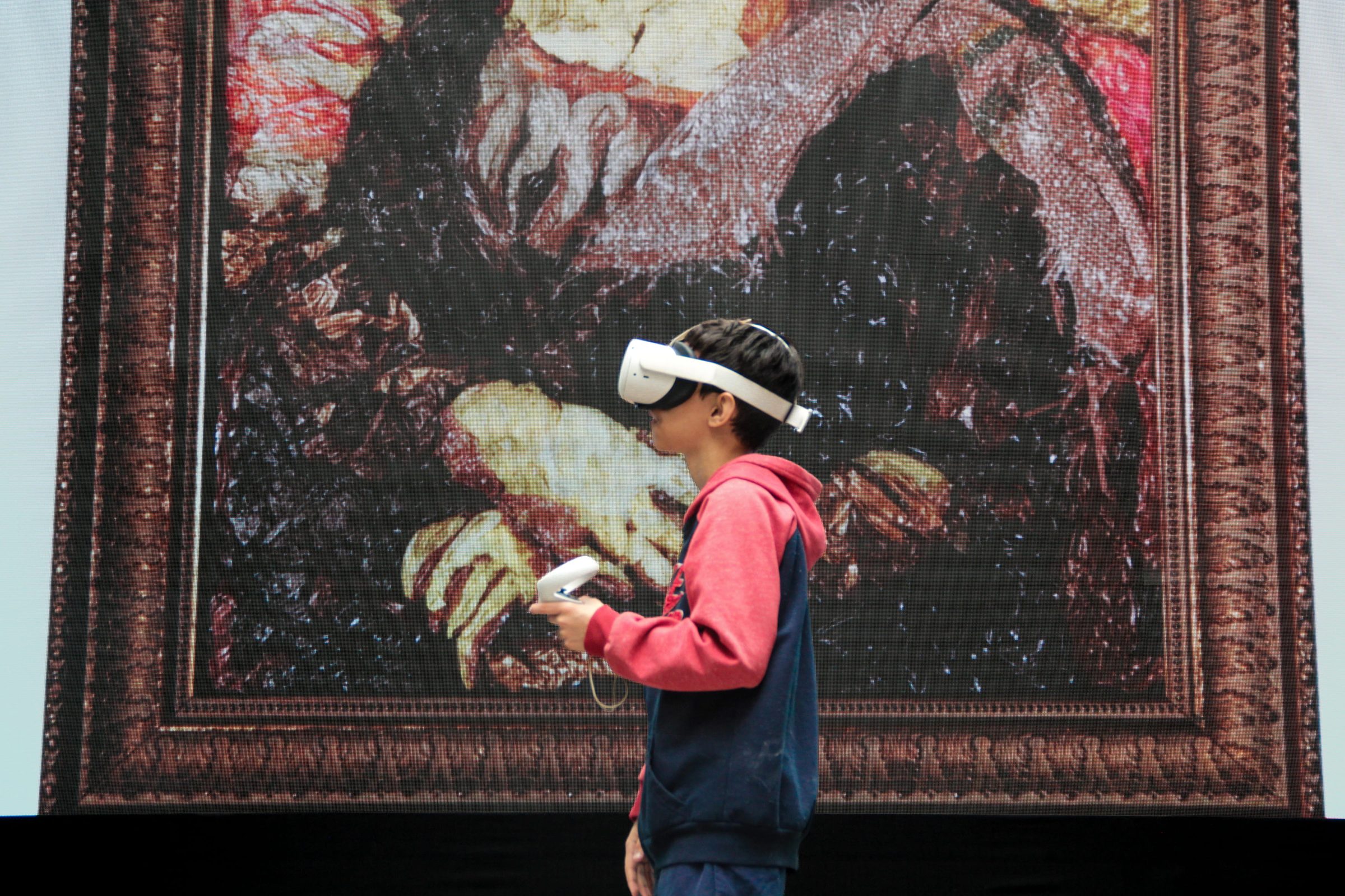 A student wearing virtual reality goggles standing in front of a work of art